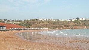 Une plage bordée de cabanes et, au loin, une ville côtière.