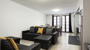 A modern living room with a black sectional sofa, a coffee table, and a dining area with a table and chairs. - Fonte Moura - With pool by HD (Vilamoura)