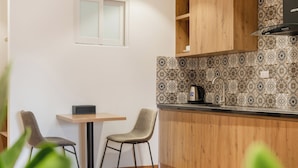 Een kleine keuken met een houten aanrecht, twee stoelen, een tafel en een raam.