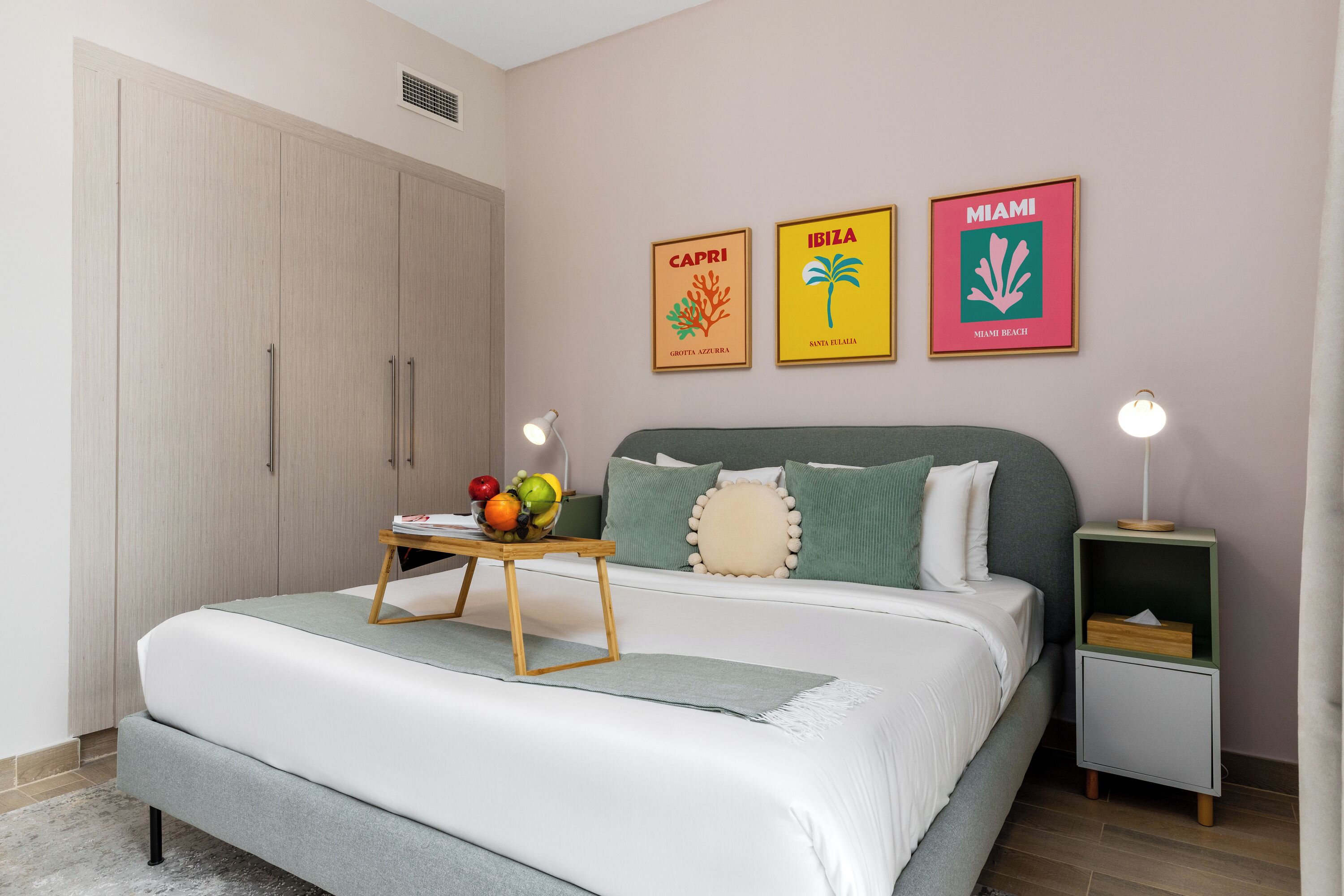 A bedroom with a bed, bedside tables, a wardrobe, and wall art.
