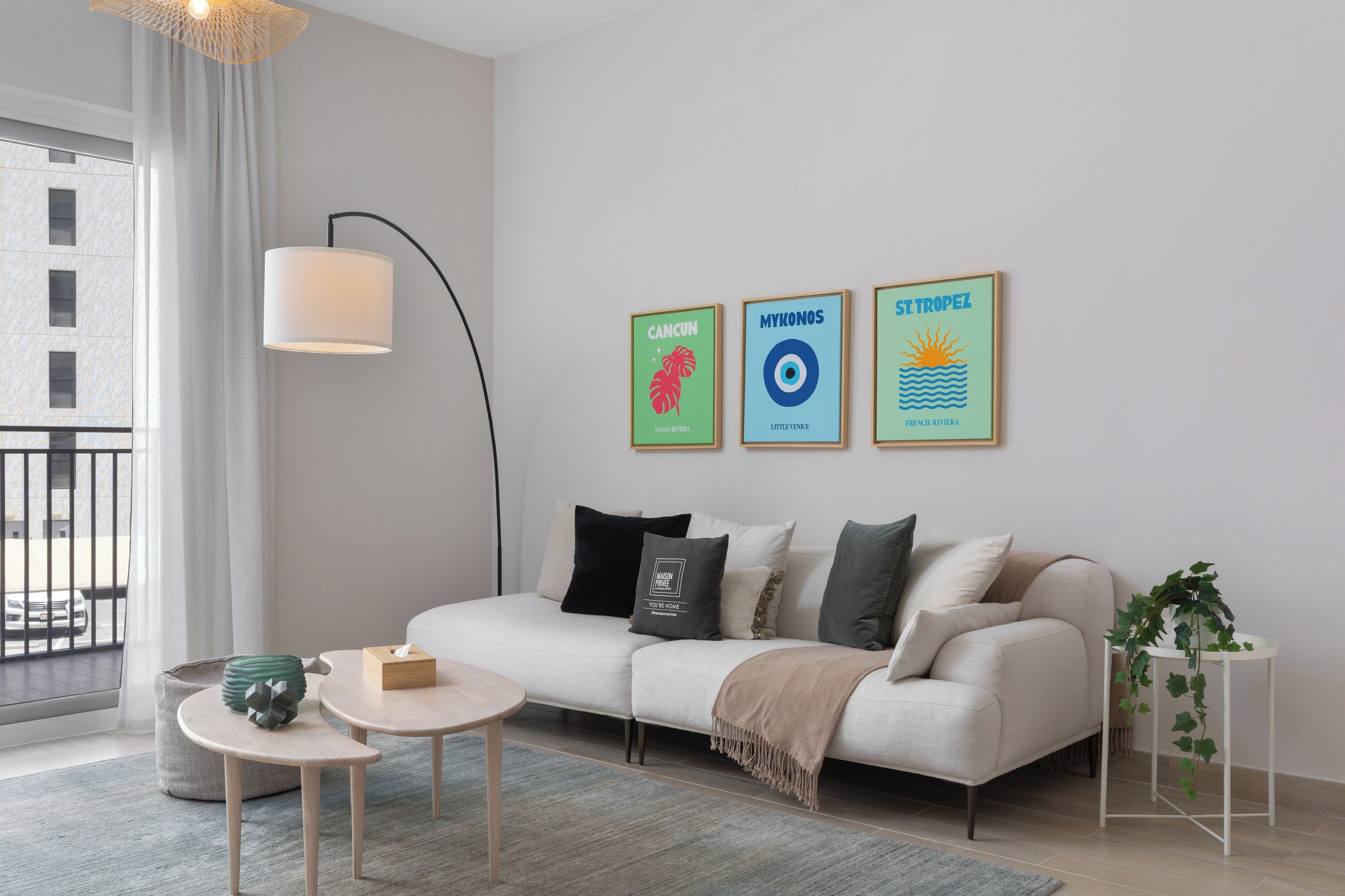 A modern living room with a sofa, a coffee table, and a floor lamp. There are three framed pictures on the wall.