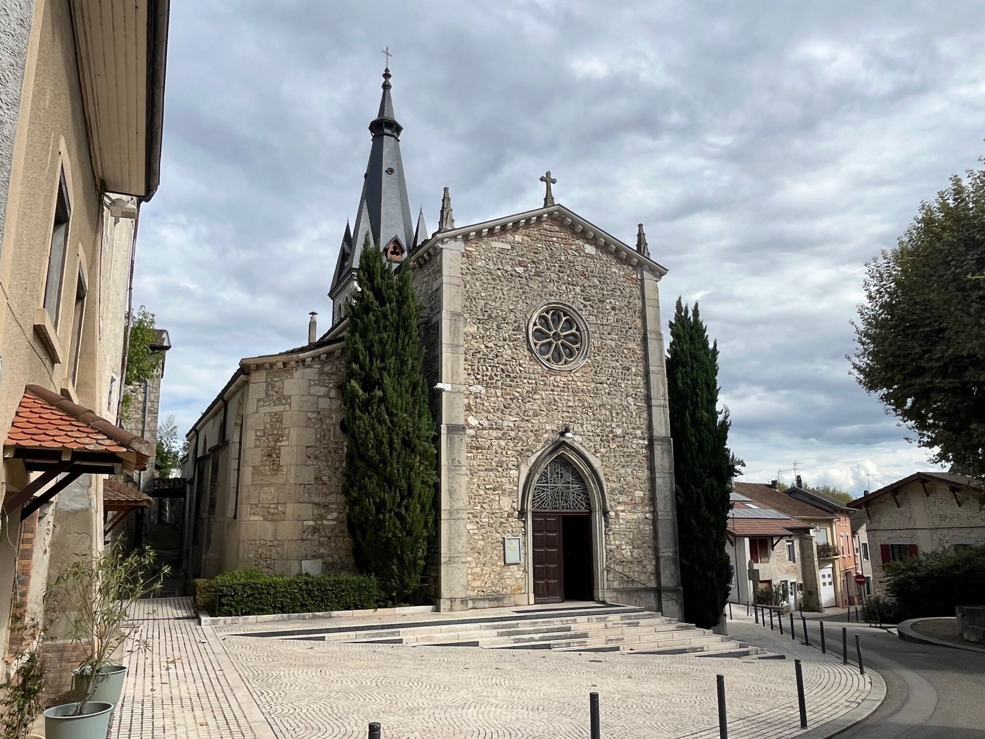 Una iglesia de piedra histórica con una aguja alta y un amplio ventanal circular.