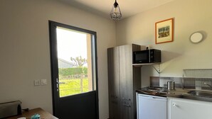 A compact kitchen with a refrigerator, microwave, and sink. There's a window with a view of greenery outside.
