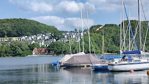 A lakeside view with boats, a tent, and a small house.