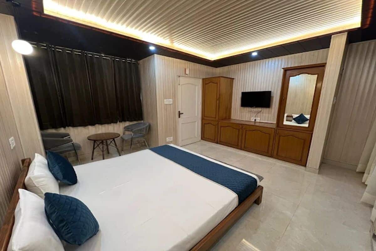 Une chambre avec un lit, une télévision, une armoire et une petite table.