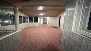 Un couloir doté d’un sol à motifs rouges, d’un plafond en bois et de grandes fenêtres sur un de ses côtés.