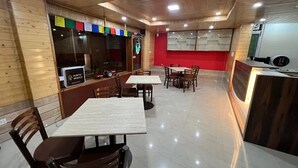 Un restaurant aux murs en bois, avec un mur d’accent rouge et un comptoir doté d’une caisse enregistreuse. Des tables et des chaises sont disposées pour accueillir les clients.