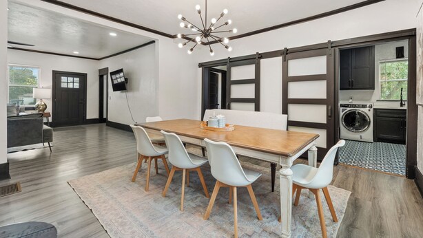 Un comedor moderno con una mesa de madera, cuatro sillas y una araña.