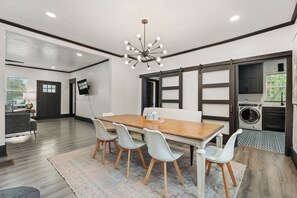 A modern dining area with a wooden table, four chairs, and a chandelier.