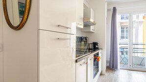 Et moderne køkken med hvide skabe, indbygget ovn og kaffemaskine.