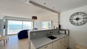 Una cocina moderna con un ventanal grande, un reloj y vistas al mar.