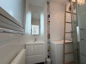 A bathroom with a white sink, mirror, and a shower with a glass door.