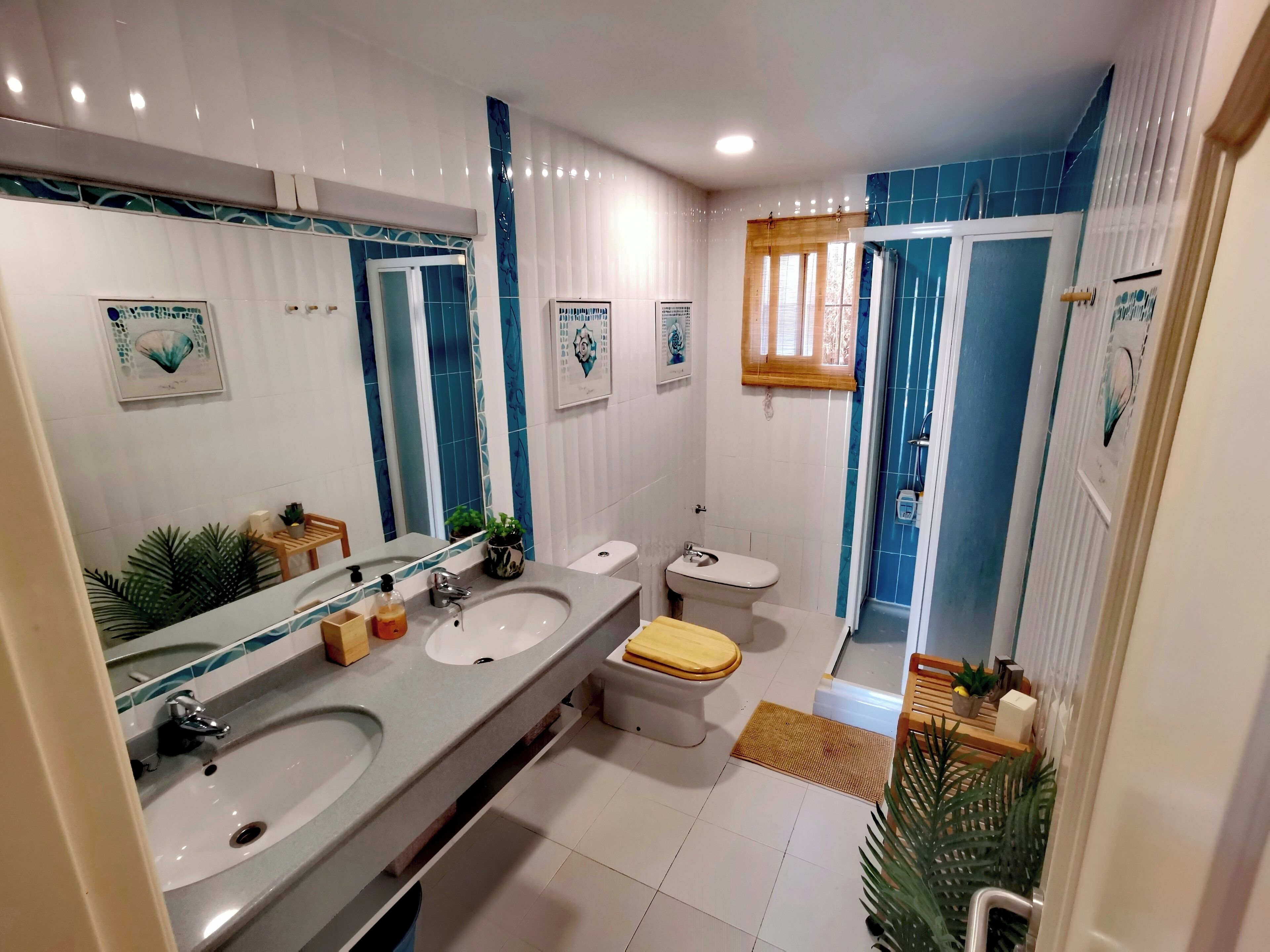 A modern bathroom with two sinks, a toilet, and a shower area.