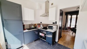 A compact kitchen with a refrigerator, microwave, sink, and a small oven. - Zen Duplex in Valenciennes city center (Valenciennes)