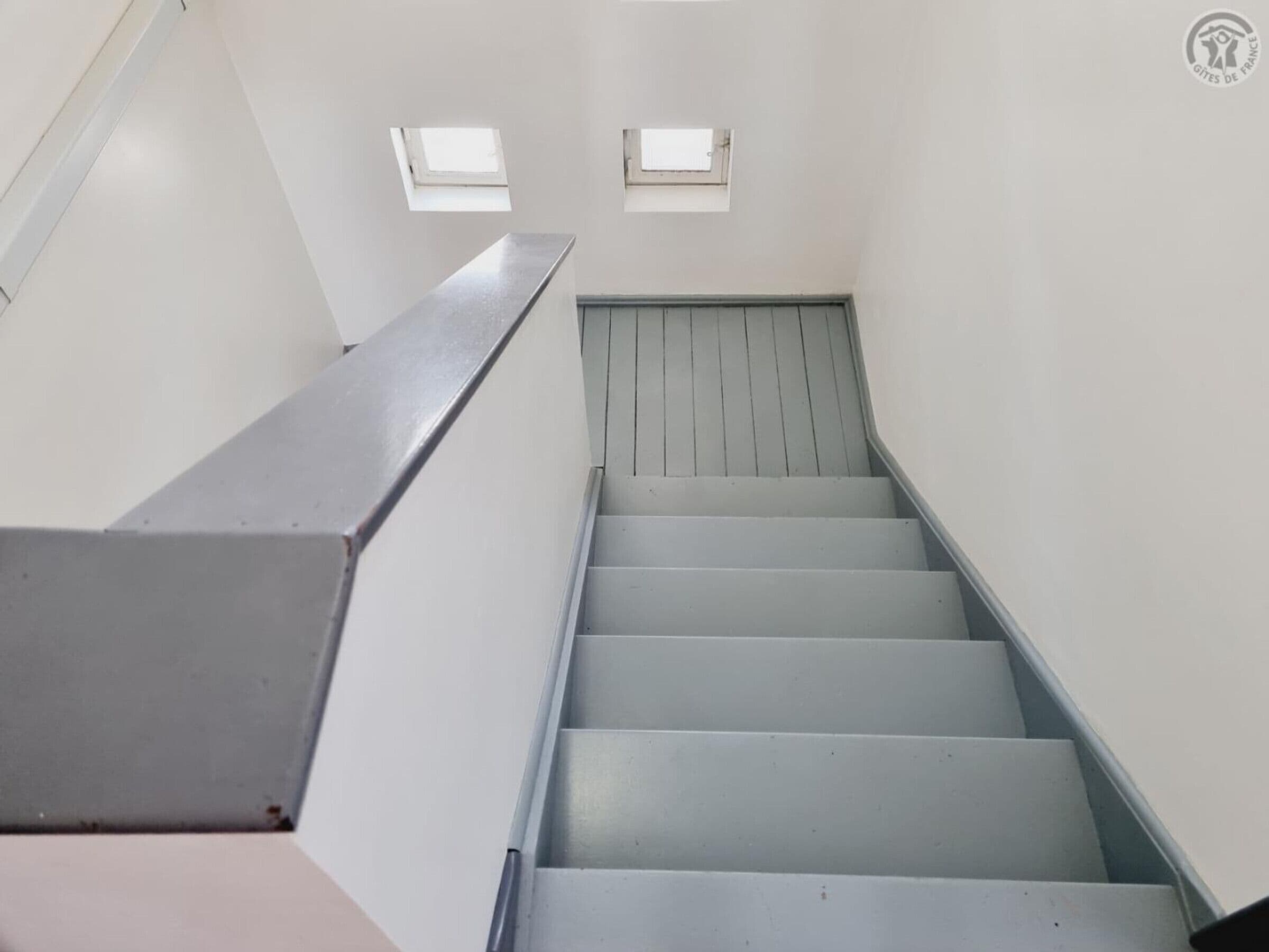 Una escalera con barandillas de metal y una pared blanca.