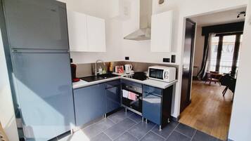 Cocina compacta con refrigerador, microondas, pileta y horno pequeño.