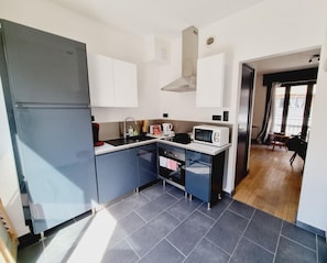 Cocina compacta con refrigerador, microondas, pileta y horno pequeño.
