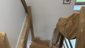 A wooden staircase with a rustic design, leading to a landing area with a window.