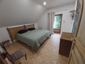 A bedroom with a bed, a small table, a chair, and a window.