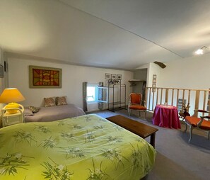 A bedroom with a bed, a chair, a table, a lamp, a window, and a wall-mounted rack. - Charming Cottage in Beaufou with Private Terrace (Beaufou)