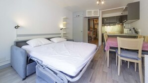 Une chambre d’hôtel de taille réduite, comprenant un lit, un bureau et une kitchenette.