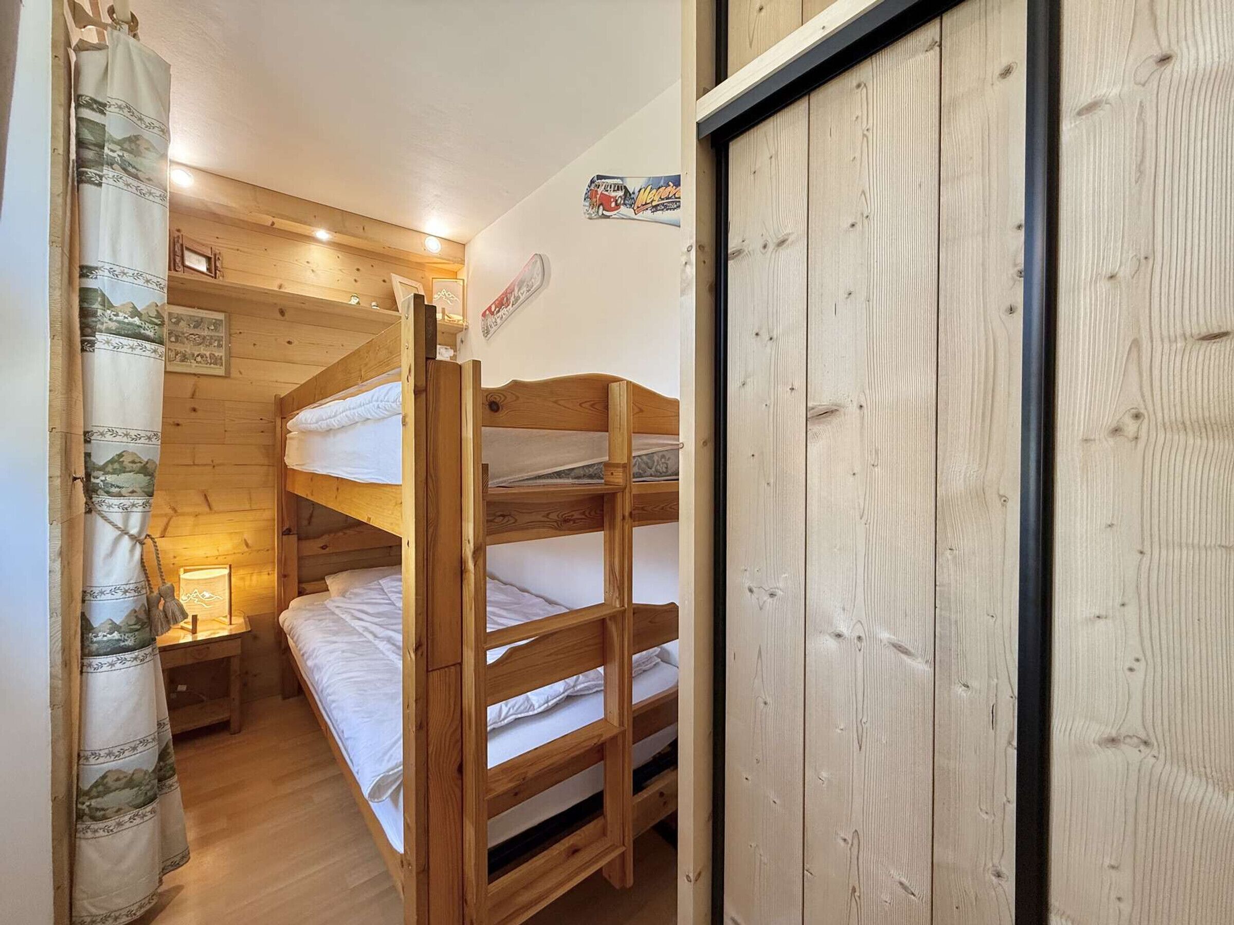 Ein Zimmer mit einem hölzernen Etagenbett, einem kleinen Nachttisch und einer Lampe.