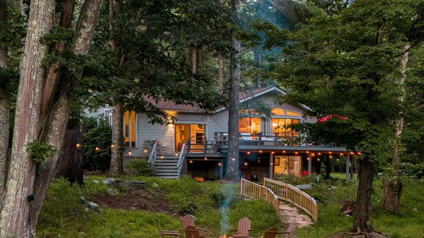 Une cabane dotée d’une terrasse, d’un foyer extérieur et d’un escalier menant à l’étage supérieur.