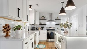 Een moderne keuken met witte kasten, roestvrijstalen apparatuur en hanglampen.