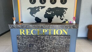 A reception desk with a marble top and a world map backdrop. - Cim Pansiyon (Antalya)