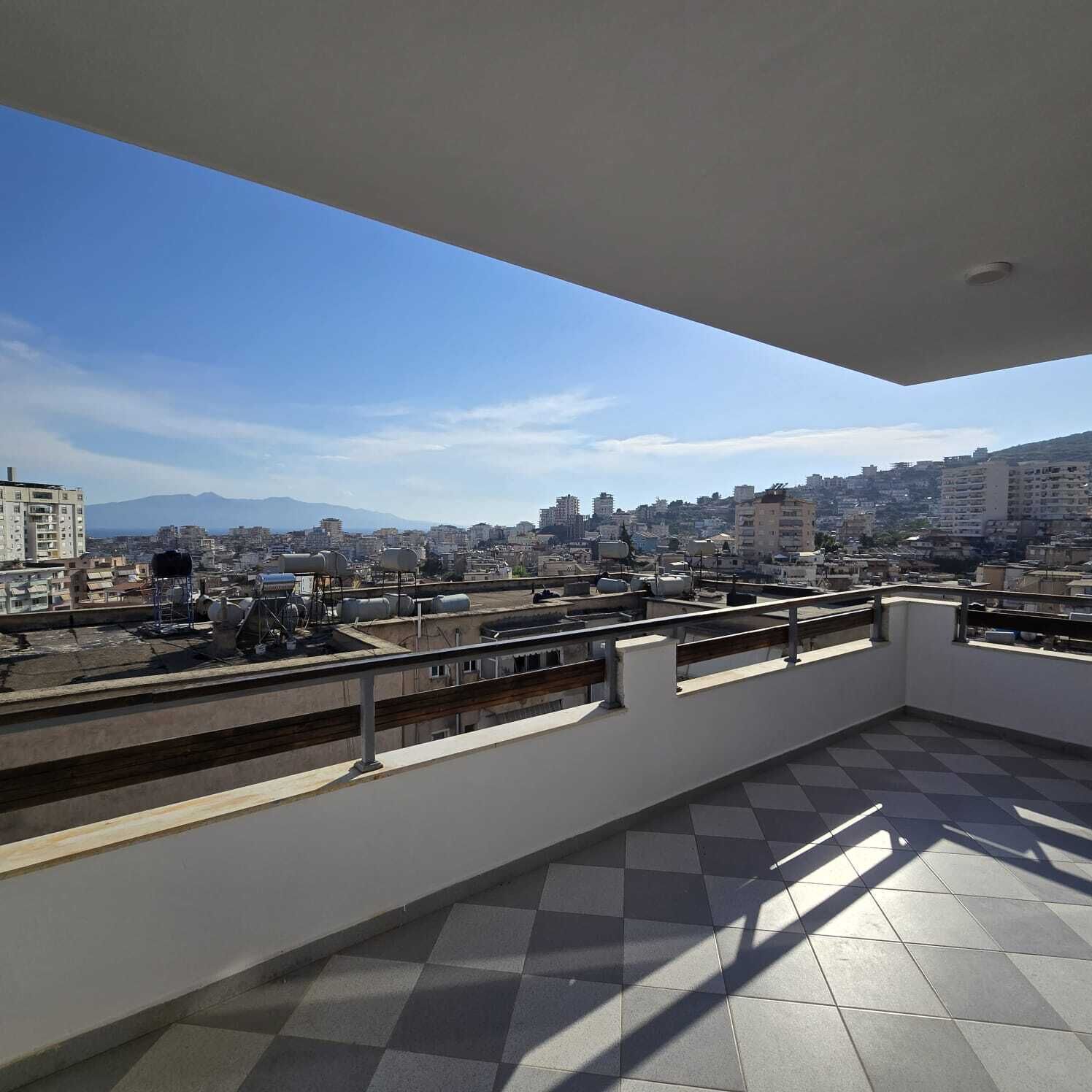 Une terrasse sur le toit offrant une vue sur la ville, avec des bâtiments et des montagnes visibles au loin.