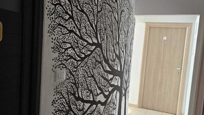 A hallway with a wall mural of a tree, a door, and a tiled floor.