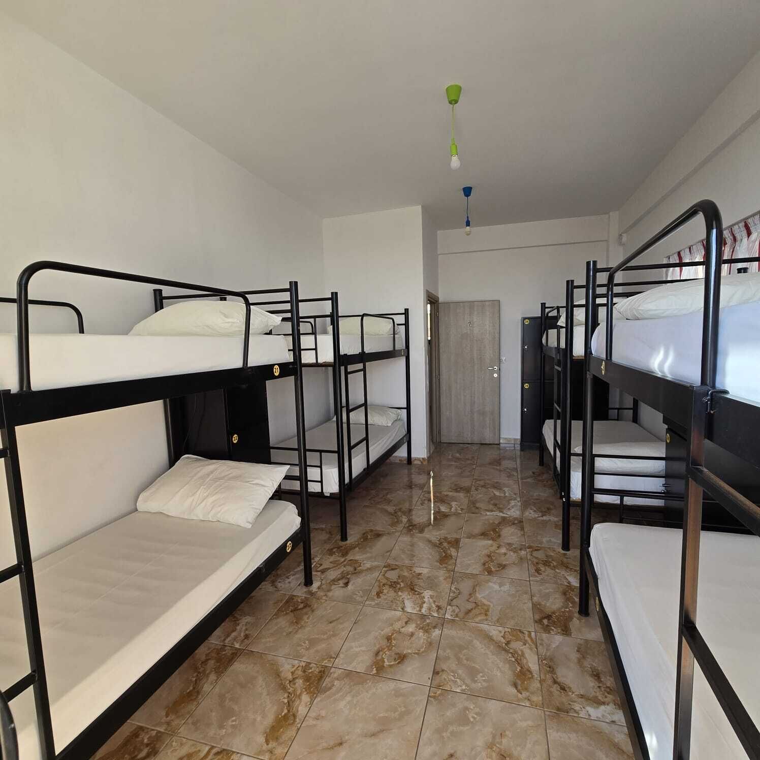 Una camera del dormitorio con letti a castello, pavimento piastrellato e una porta sullo sfondo.