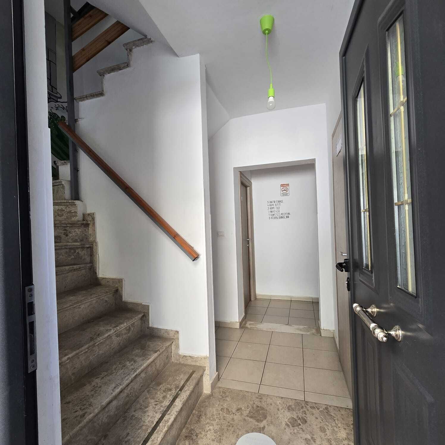 A hallway with a staircase, a door, and a sign with text.