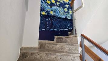 Un escalier orné d’un tableau bleu représentant une scène nocturne avec des étoiles et un arbre.