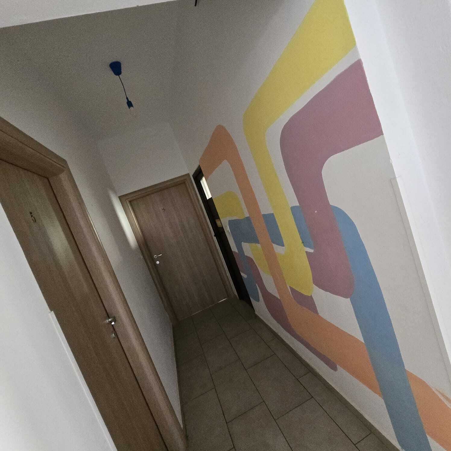 A hallway with a wooden door and a colorful abstract wall.