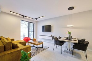 A modern living room with a sofa, coffee table, and dining area with chairs.