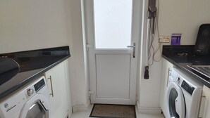 Une buanderie équipée d’un lave-linge, d’un sèche-linge et d’une porte donnant sur une autre pièce.