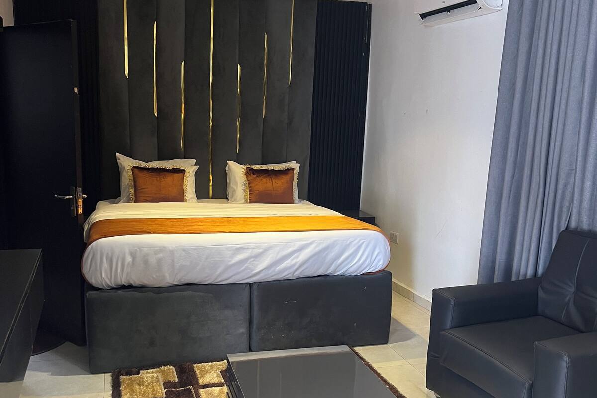 Een moderne slaapkamer met een groot bed, een grijze bank en een salontafel.