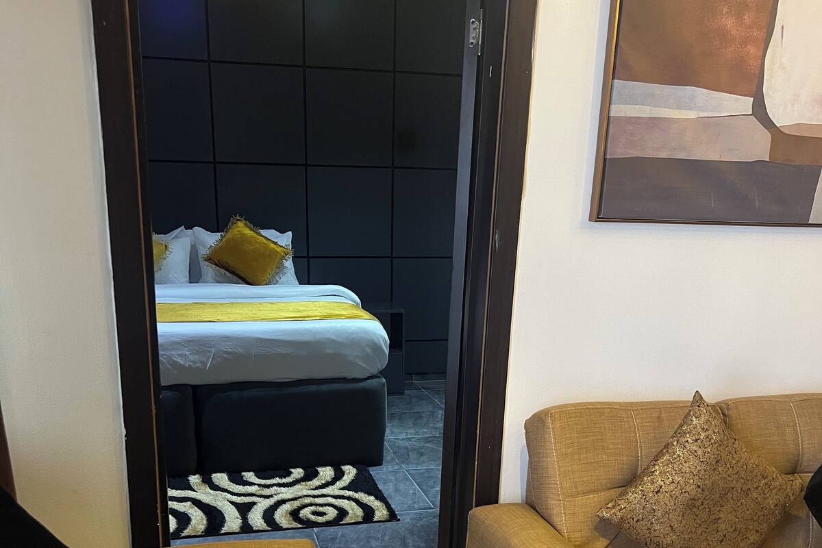 Een moderne woonkamer met een bank, een salontafel en een bed met een kamerkleed met dessin.