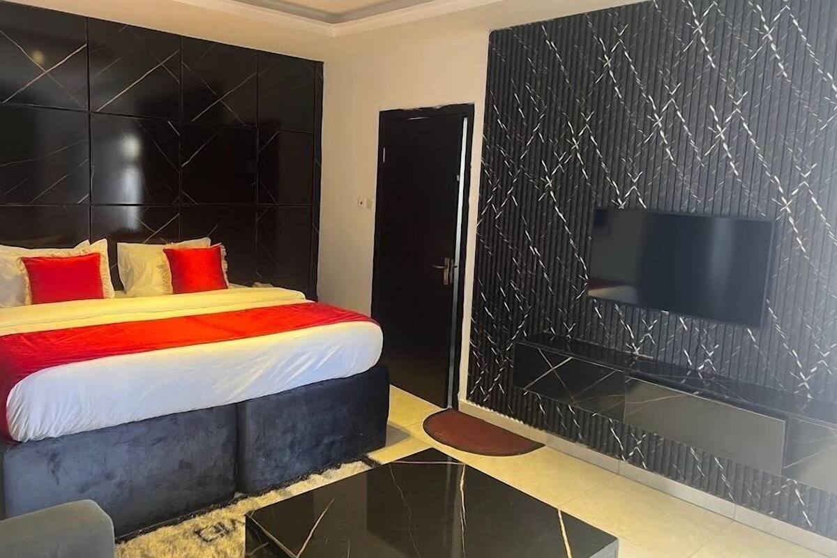 Een moderne slaapkamer met een bed, een televisie en een zwarte garderobe.