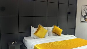 Quarto moderno com uma cama grande, uma mesa de cabeceira e uma cabeceira escura.