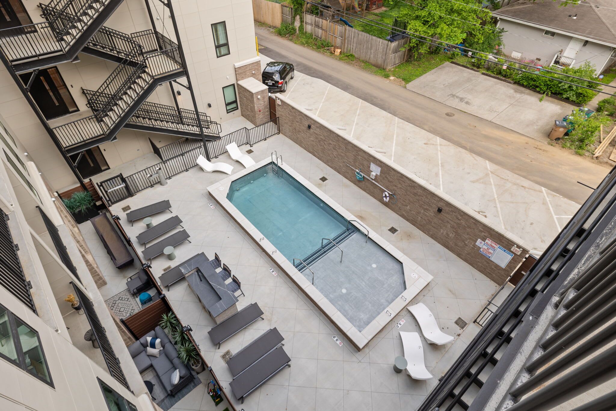 A rooftop pool with lounge chairs and a staircase leading to an upper floor.