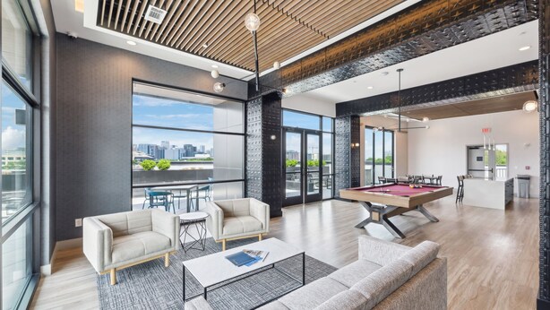 A modern living room with a pool table, sofas, and a city view. - Stylish Music Row studio unit near Broadway (Nashville)