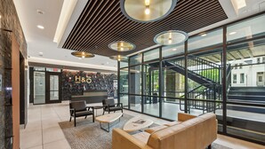 A modern hotel lobby with a reception desk, seating area, and large windows offering views of the outside. - Stylish Music Row studio unit near Broadway (Nashville)