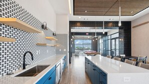 A modern kitchen with a patterned backsplash, blue cabinets, and a large island with seating. - Stylish Music Row studio unit near Broadway (Nashville)