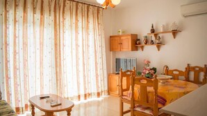 A cozy room with a dining table, chairs, a TV, and a cabinet. - Carmina Apartments (Carboneras)