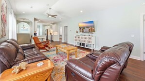A spacious living room with leather sofas, a wooden coffee table, and a colorful rug. - Flamingo Hideaway Modern House w Elevator (North Myrtle Beach)