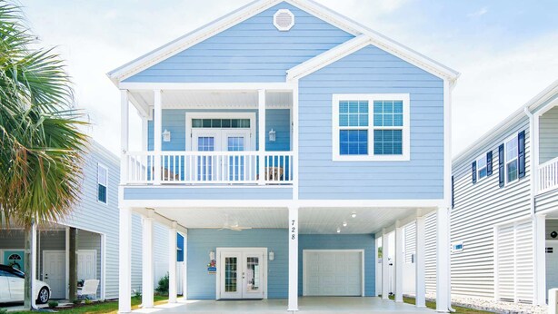 A two-story house with a covered front porch, a garage, and a small balcony.