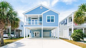 A two-story residential building with a balcony, a garage, and a driveway.