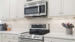 A kitchen with a stainless steel microwave, oven, and stove. - Flamingo Hideaway Modern House w Elevator (North Myrtle Beach)